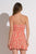 Woman wearing a coral patterned dress against a white background