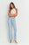 Woman wearing light blue jeans and a white top against a white background