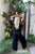 Person in black outfit standing in a garden with plants and a door in the background