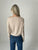 Person wearing a beige long-sleeve top and blue jeans against a plain background
